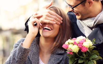 Young romantic couple, man surprising woman with flowers