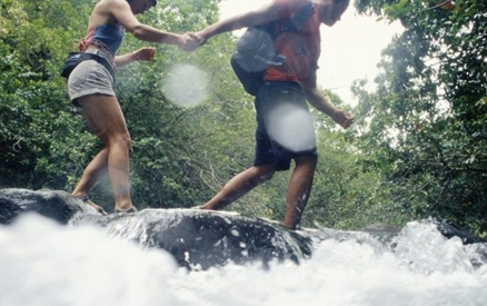 Man and woman hiking across river, low angle view